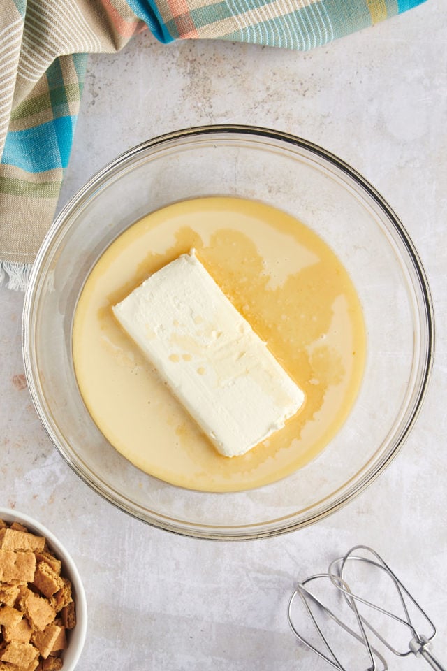 Overhead view of cream cheese, condensed milk, and vanilla in mixing bowl