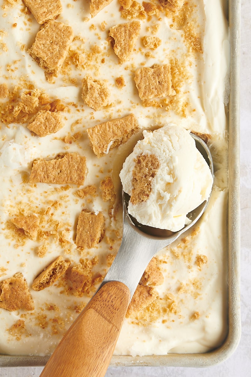 Overhead view of ice cream scooper in pan of cheesecake ice cream