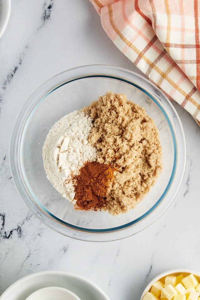 overhead view of flour, brown sugar, cinnamon, and salt in a glass mixing bowl