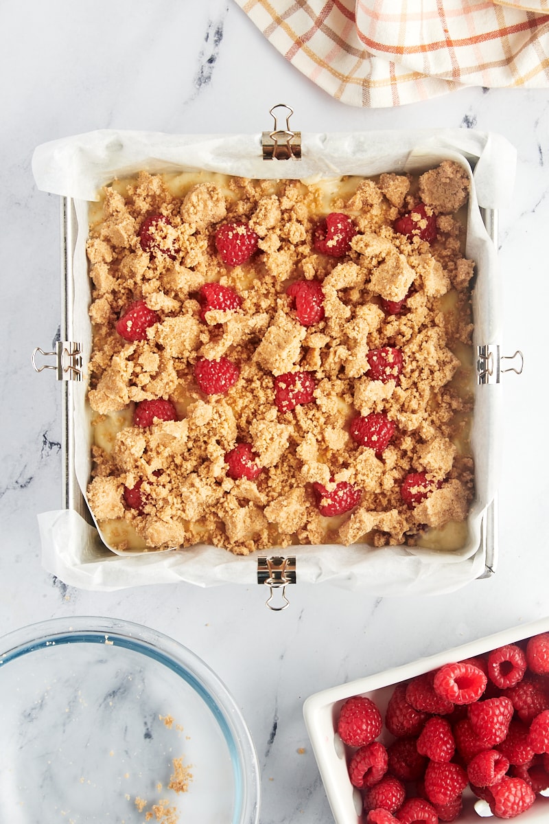 Assembled raspberry coffee cake, with batter, fresh raspberries, and crumb topping, ready for baking.