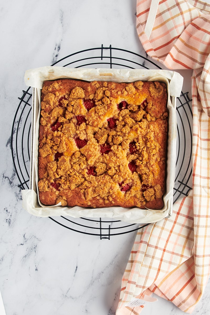 overhead view of freshly baked raspberry coffee cake in a baking pan on a wire rack