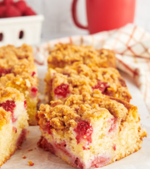 slices of raspberry coffee cake on a wooden board topped with parchment paper