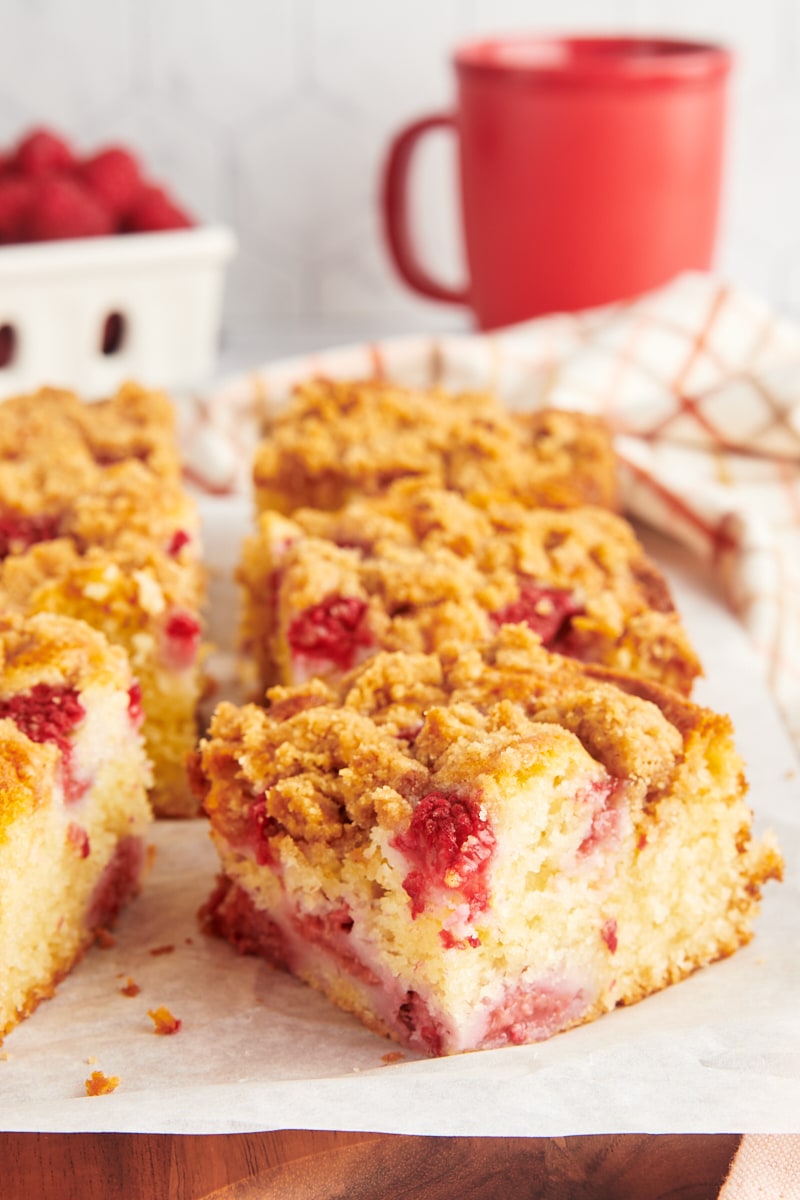 slices of raspberry coffee cake on a wooden board topped with parchment paper