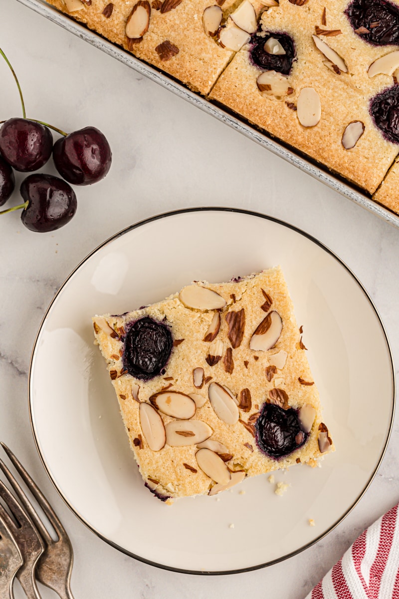 Overhead view of cherry almond sheet cake in pan and on plate