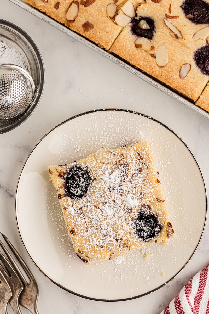 Overhead view of cherry almond sheet cake on plate and pin sheet pan