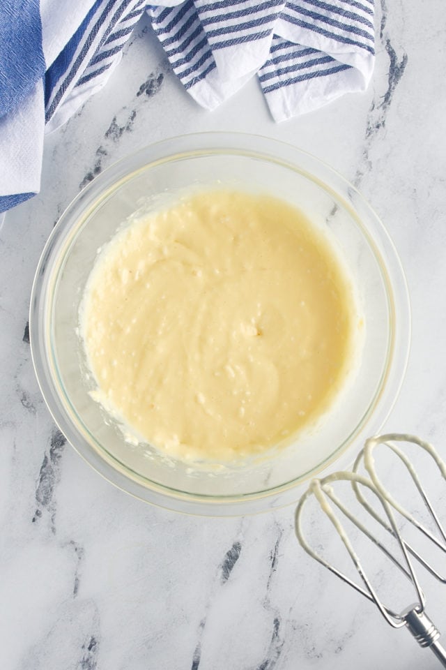 Overhead view of cream cheese topping mixture in glass mixing bowl