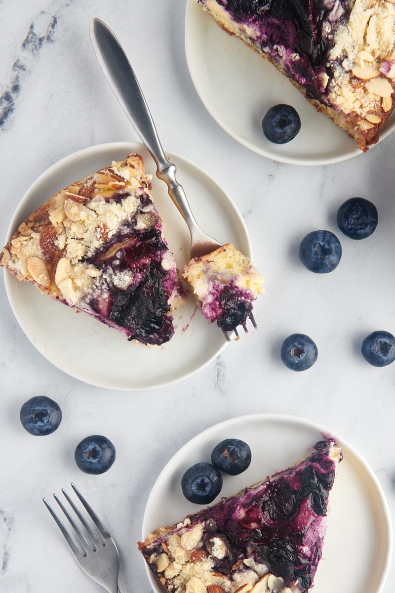 Overhead view of 3 slices of blueberry cream cheese coffee cake on white plates