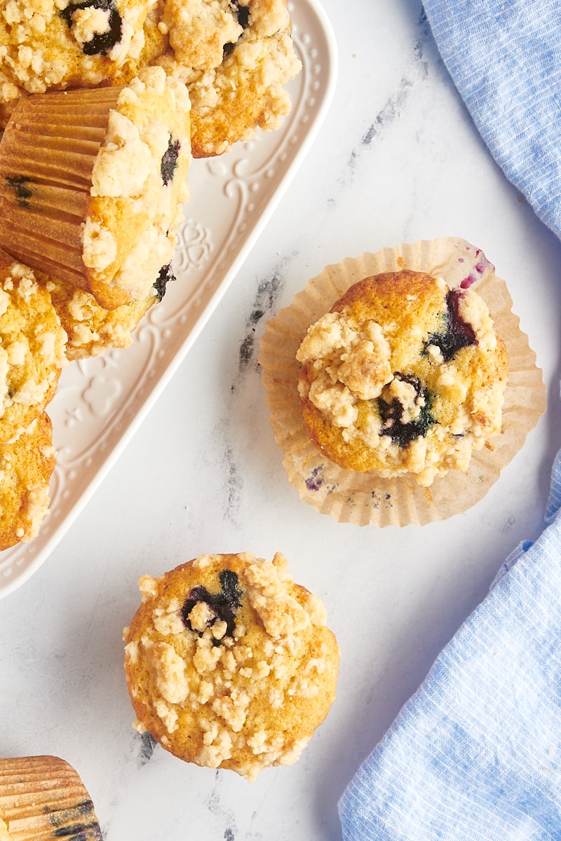 Overhead view of blueberry crumb muffins on countertop, with one set on wrapper