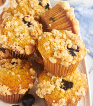 Stack of blueberry crumb muffins on white platter
