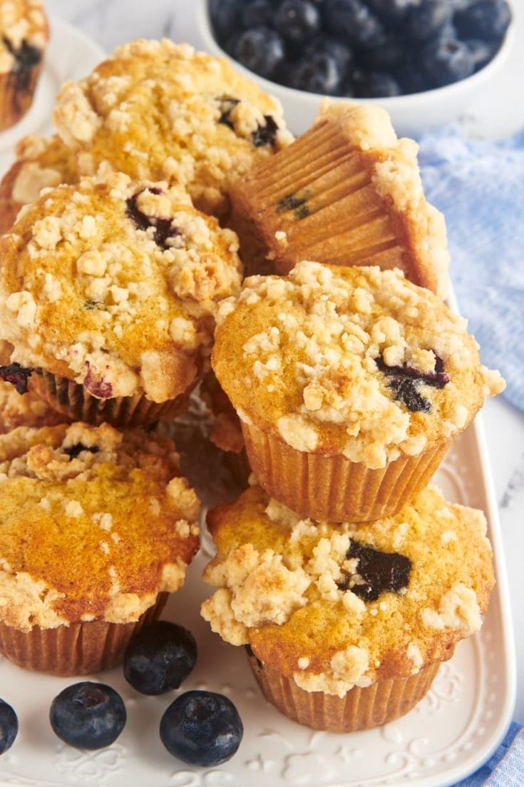 Stack of blueberry crumb muffins on white platter