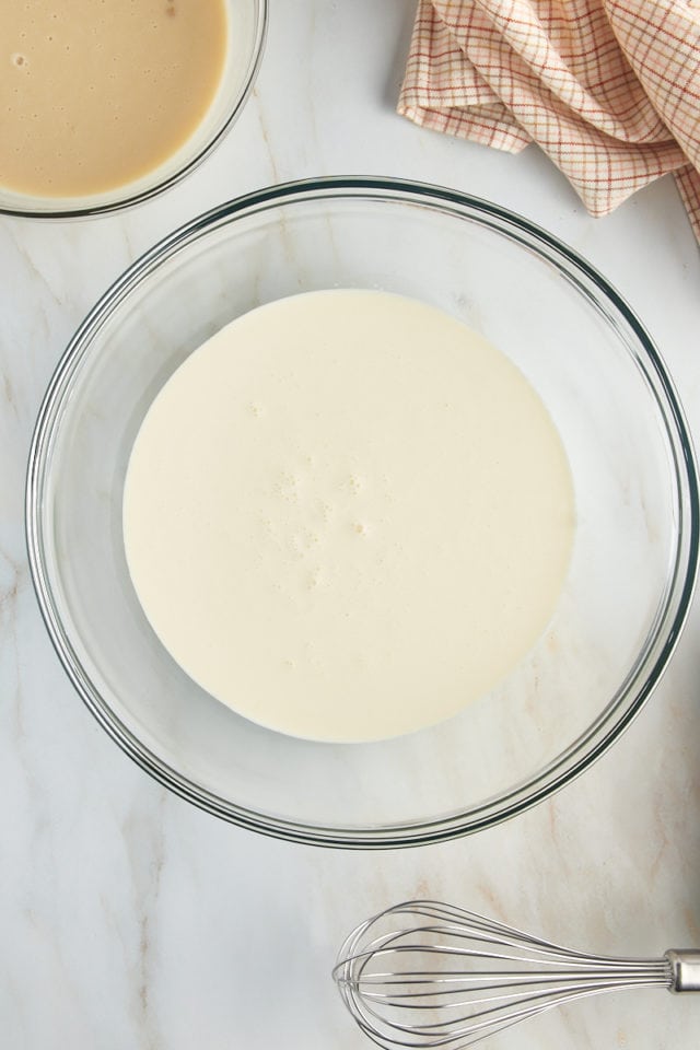 overhead view of heavy whipping cream in a glass mixing bowl