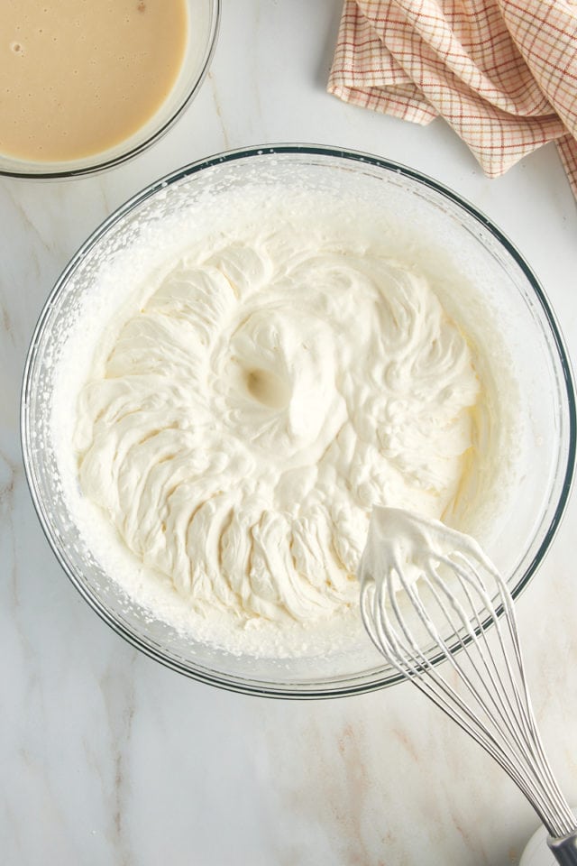 overhead view of whipped cream in a glass mixing bowl