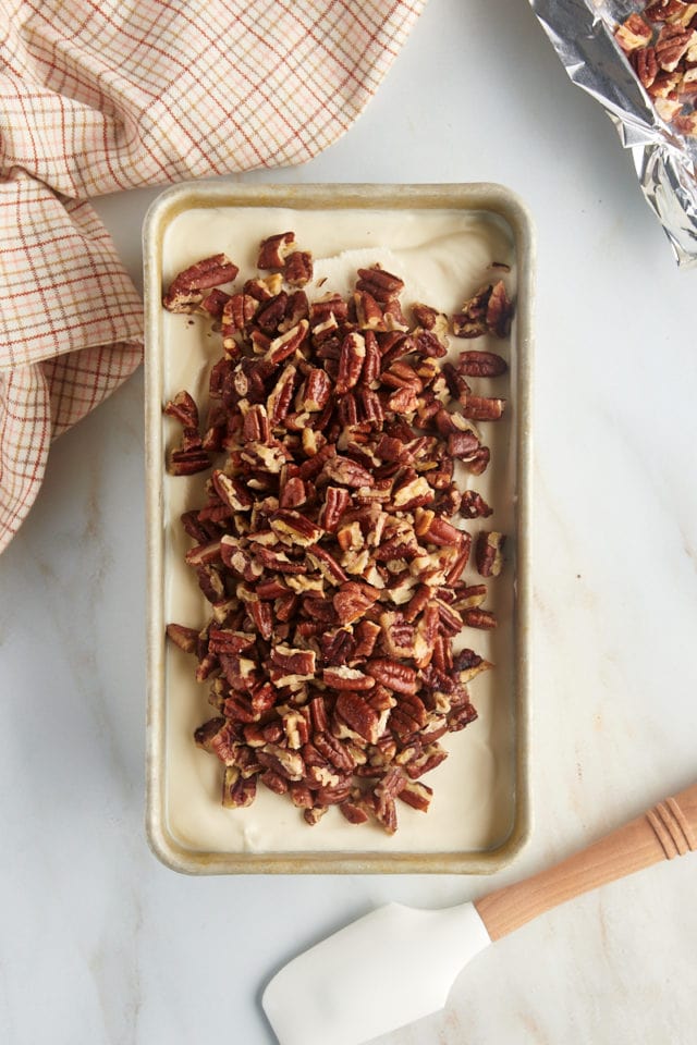 overhead view of toasted pecans added to ice cream in a metal loaf pan