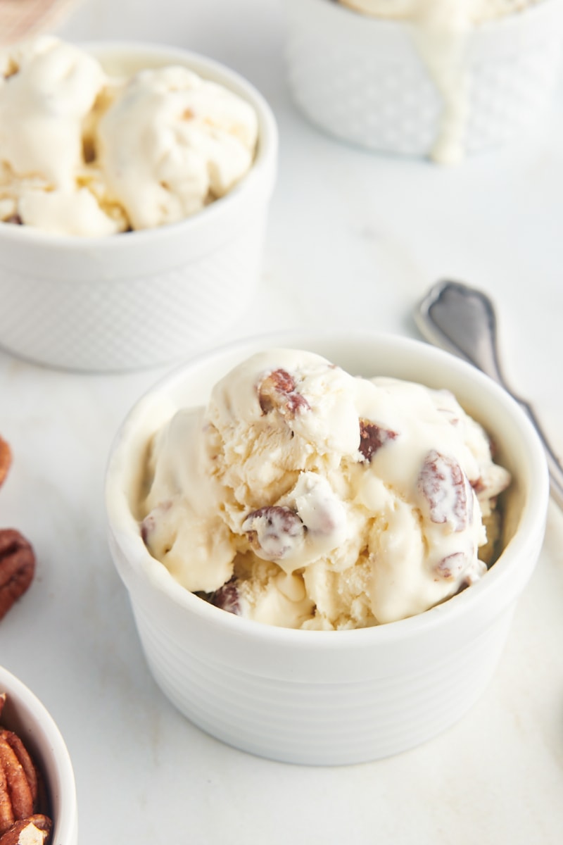 butter pecan ice cream in a white ramekin with more ice cream in the background