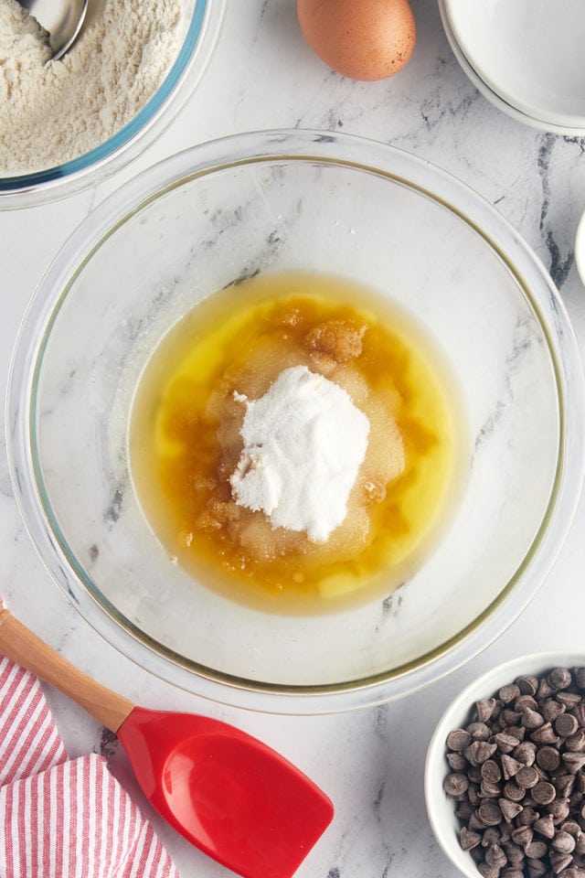 overhead view of melted butter, brown sugar, and sugar in a glass mixing bowl