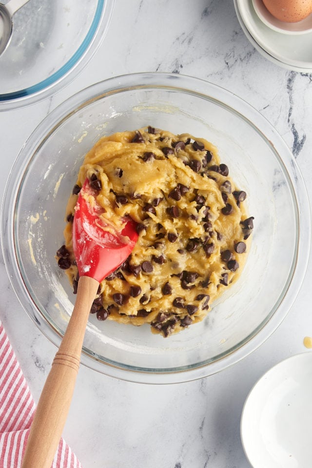 overhead view of mixed chocolate chip cookie cake dough in a glass mixing bowl