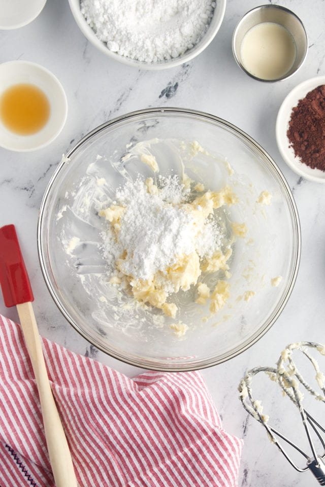 overhead view of creamed butter and confectioners' sugar in a glass mixing bowl