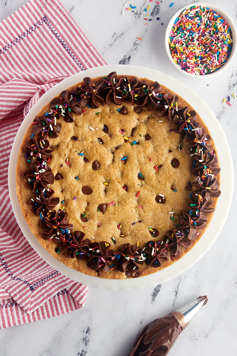 overhead view of chocolate chip cookie cake decorated with chocolate frosting and rainbow sprinkles
