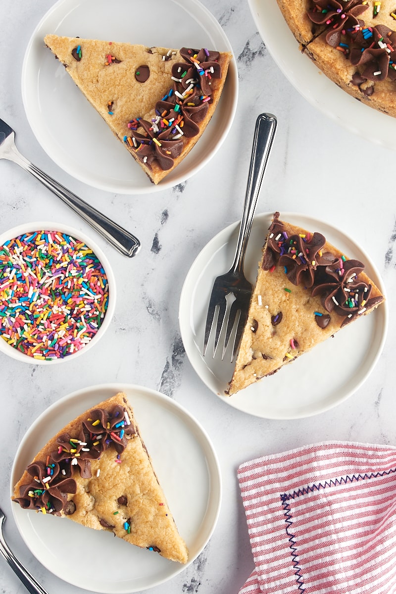 overhead view of slices of chocolate chip cookie cake on white plates