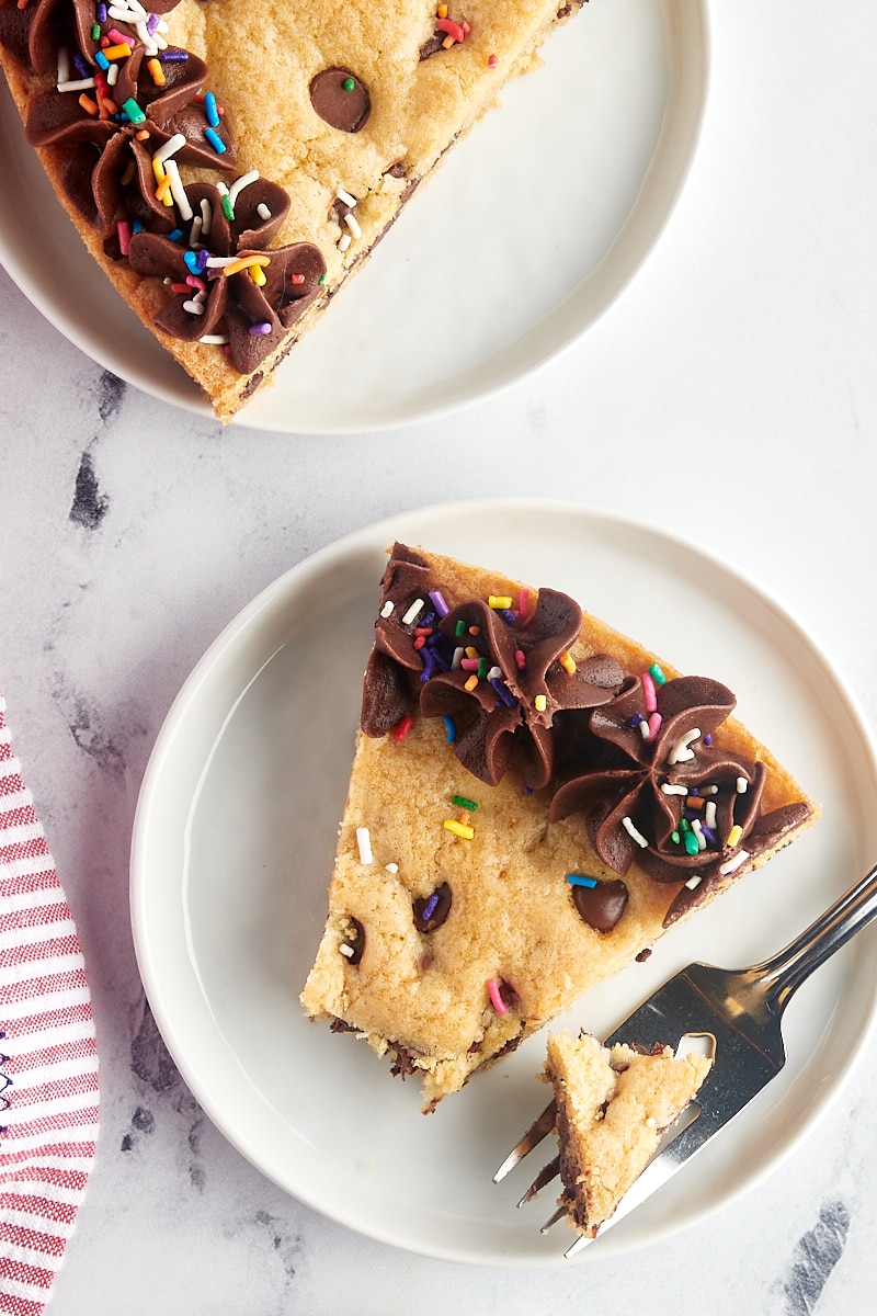 overhead view of a slice of chocolate chip cookie cake on a white plate with a bite on a fork