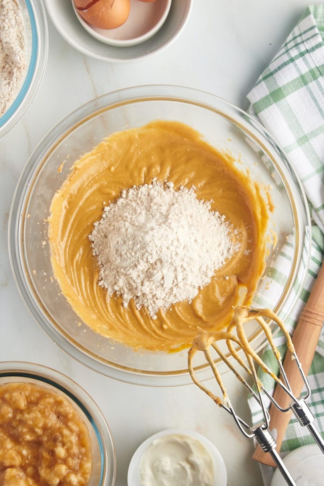 Overhead view of dry ingredients adding to batter in bowl