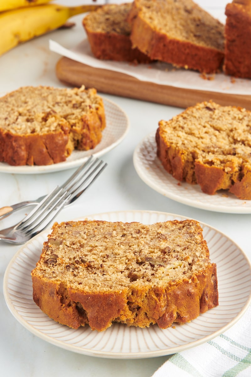 Slices of peanut butter banana bread on white plates and cutting board