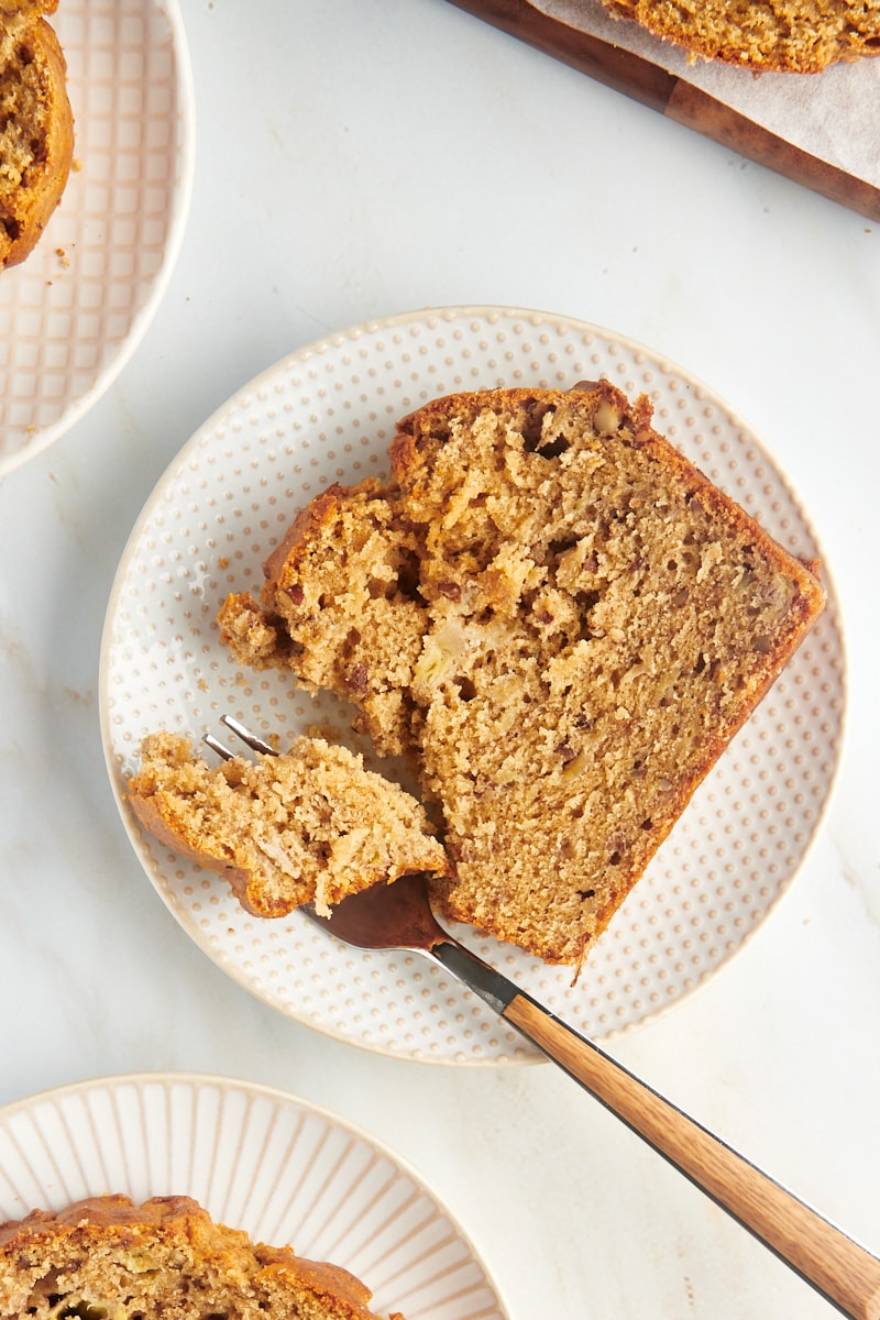 Overhead view of peanut butter banana bread slice on white plate with fork