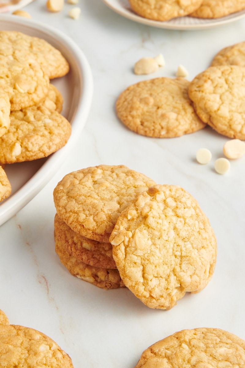 Stack of white chocolate macadamia nut cookies with additional cookies in the background and foreground.