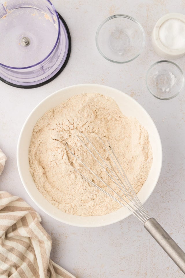 Overhead view of dry cake ingredients with whisk in bowl