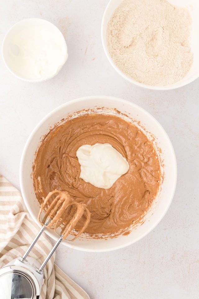 Overhead view of sour cream added to chocolate hazelnut cake batter