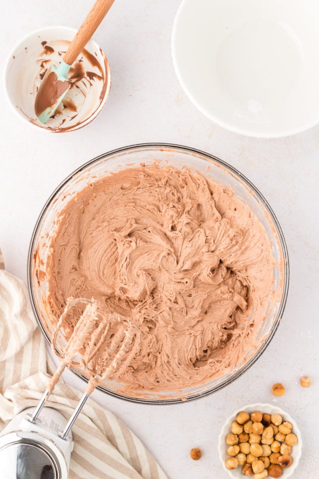 Overhead view of Nutella cream cheese frosting in mixing bowl with hand mixer