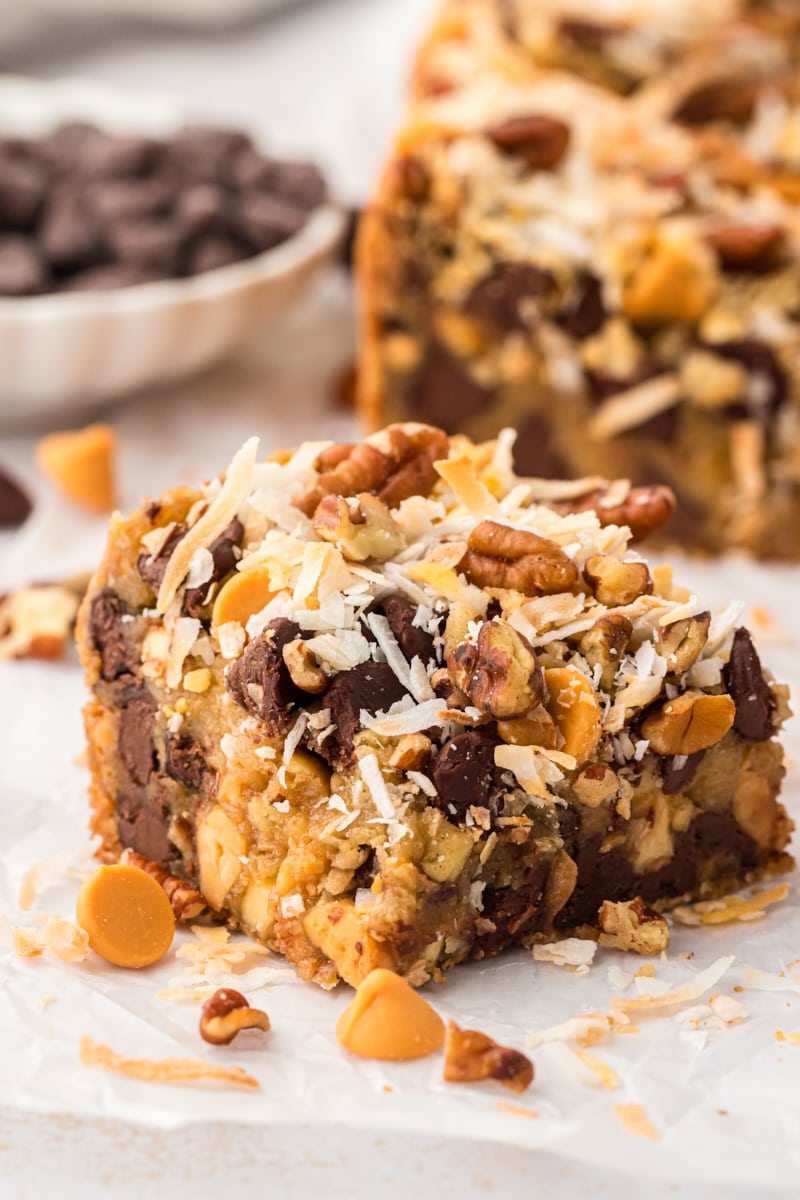 a toffee square on parchment paper with additional bars in the background