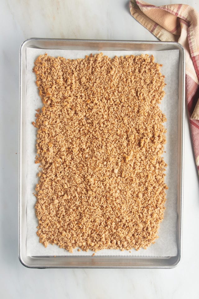 Overhead view of breadcrumbs on parchment-lined baking sheet