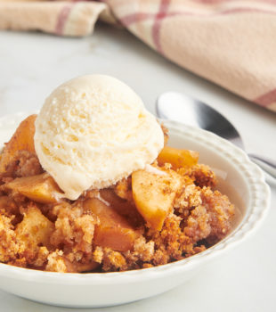 Apple Brown Betty in white bowl with scoop of ice cream on top