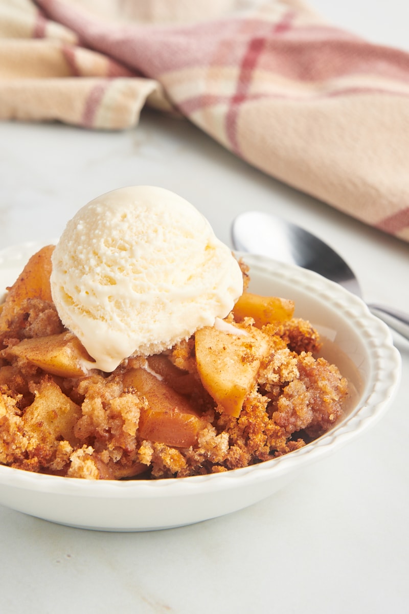 Apple Brown Betty in white bowl with scoop of ice cream on top