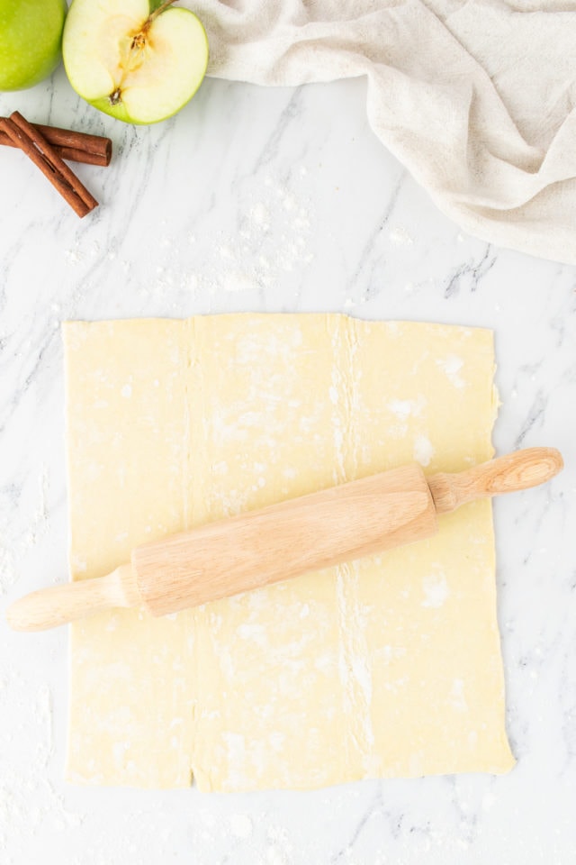 overhead view of rolled puff pastry on a marble surface