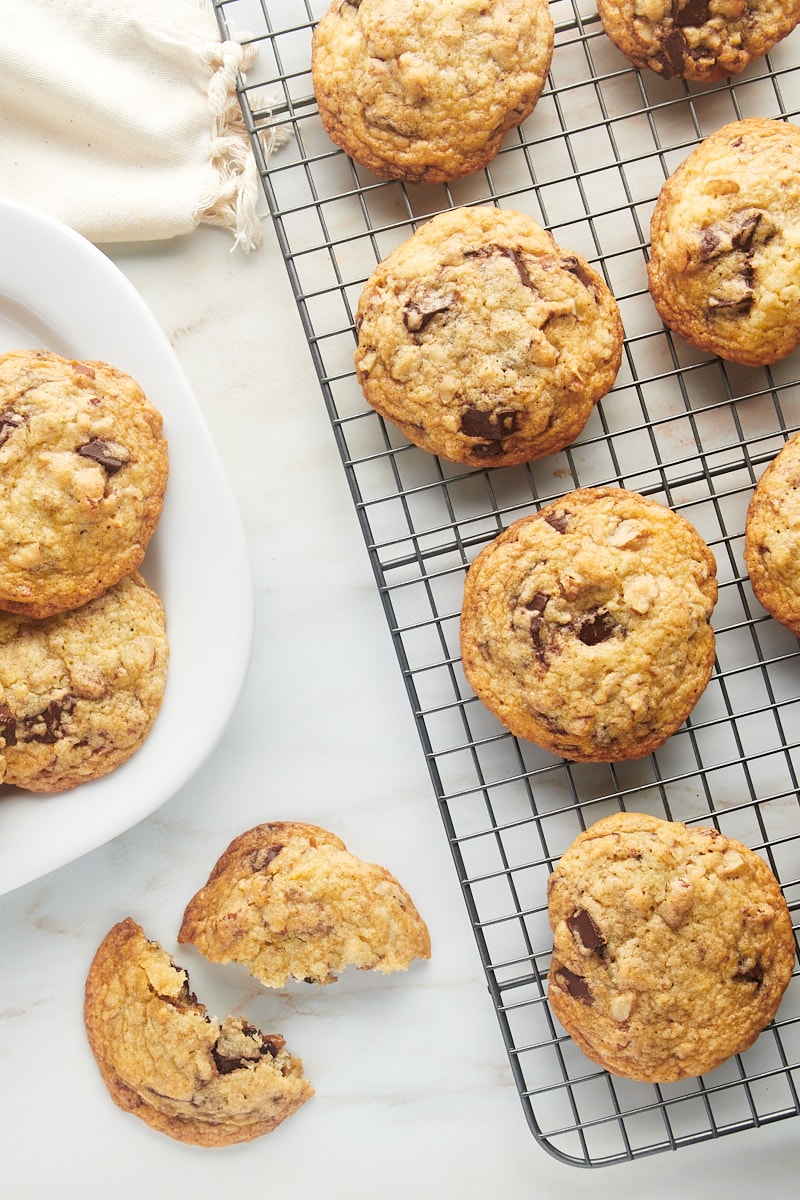 Overhead view of chocolate chunk pecan cookies on wire rack, plate, and countertop