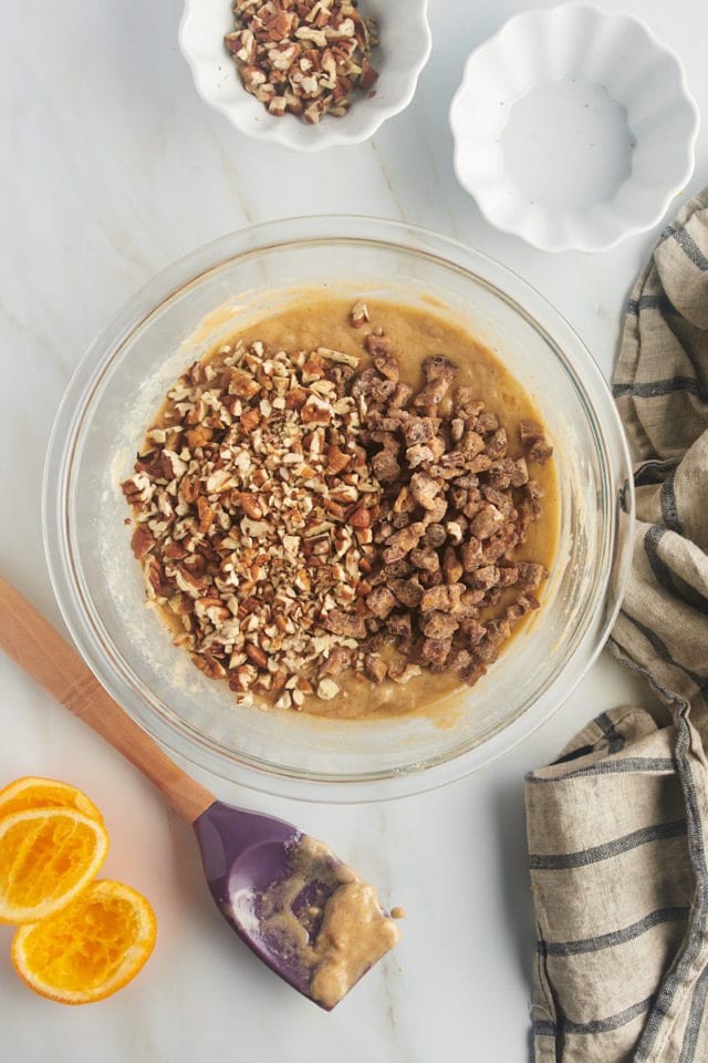 overhead view of dates and nuts added to muffin batter in a glass mixing bowl