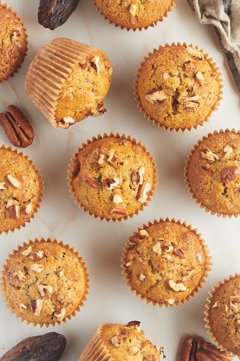 overhead view of date nut muffins scattered on a countertop