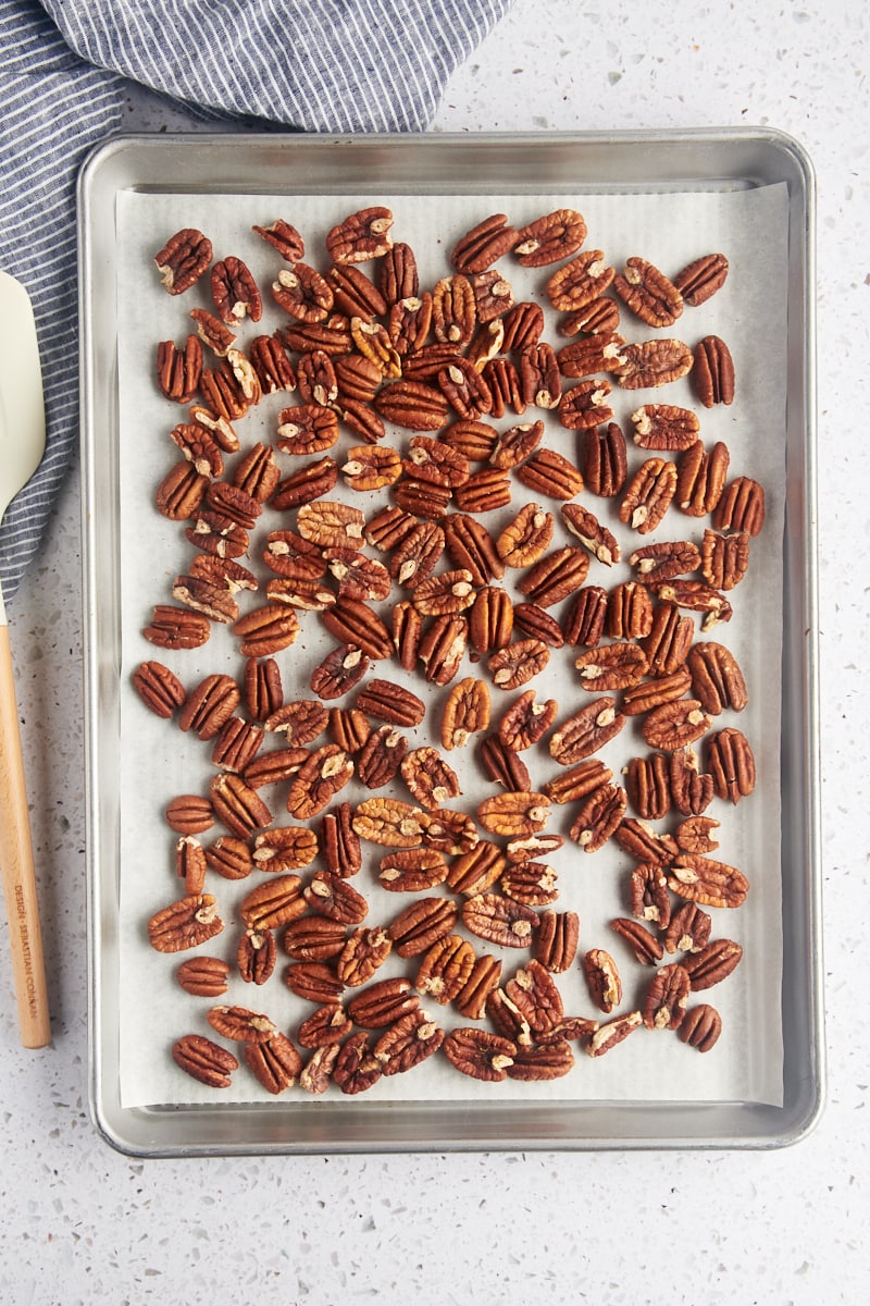 overhead view of toasted pecans on a parchment-lined baking sheet