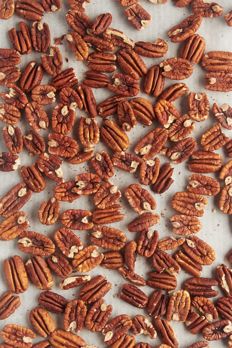 overhead view of toasted pecans on a sheet of parchment paper