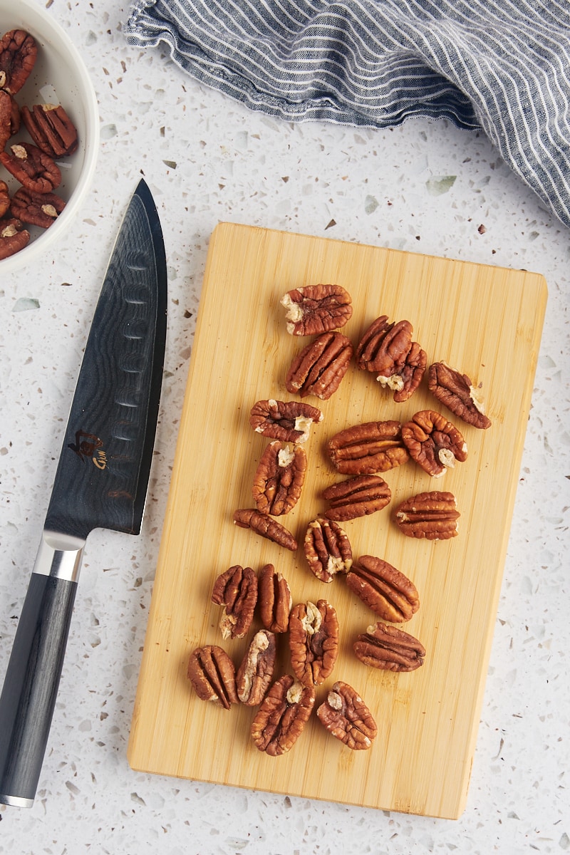 overhead view of toasted pecans on a wooden cutting board