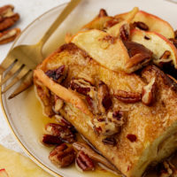 Plate of apple cinnamon baked French toast with maple syrup and pecans