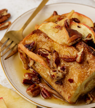 Plate of apple cinnamon baked French toast with maple syrup and pecans