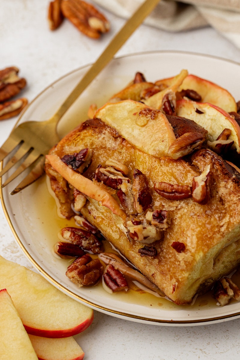 Plate of apple cinnamon baked French toast with maple syrup and pecans