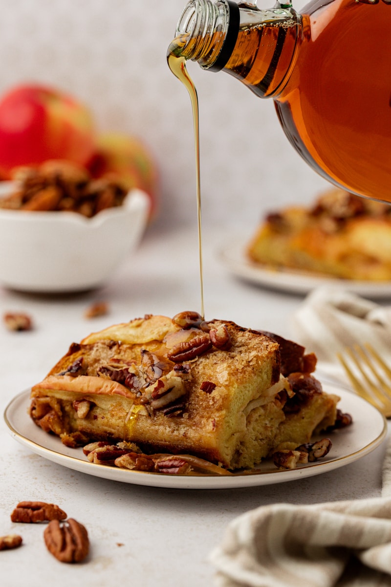 Pouring maple syrup onto plate of apple cinnamon baked French toast