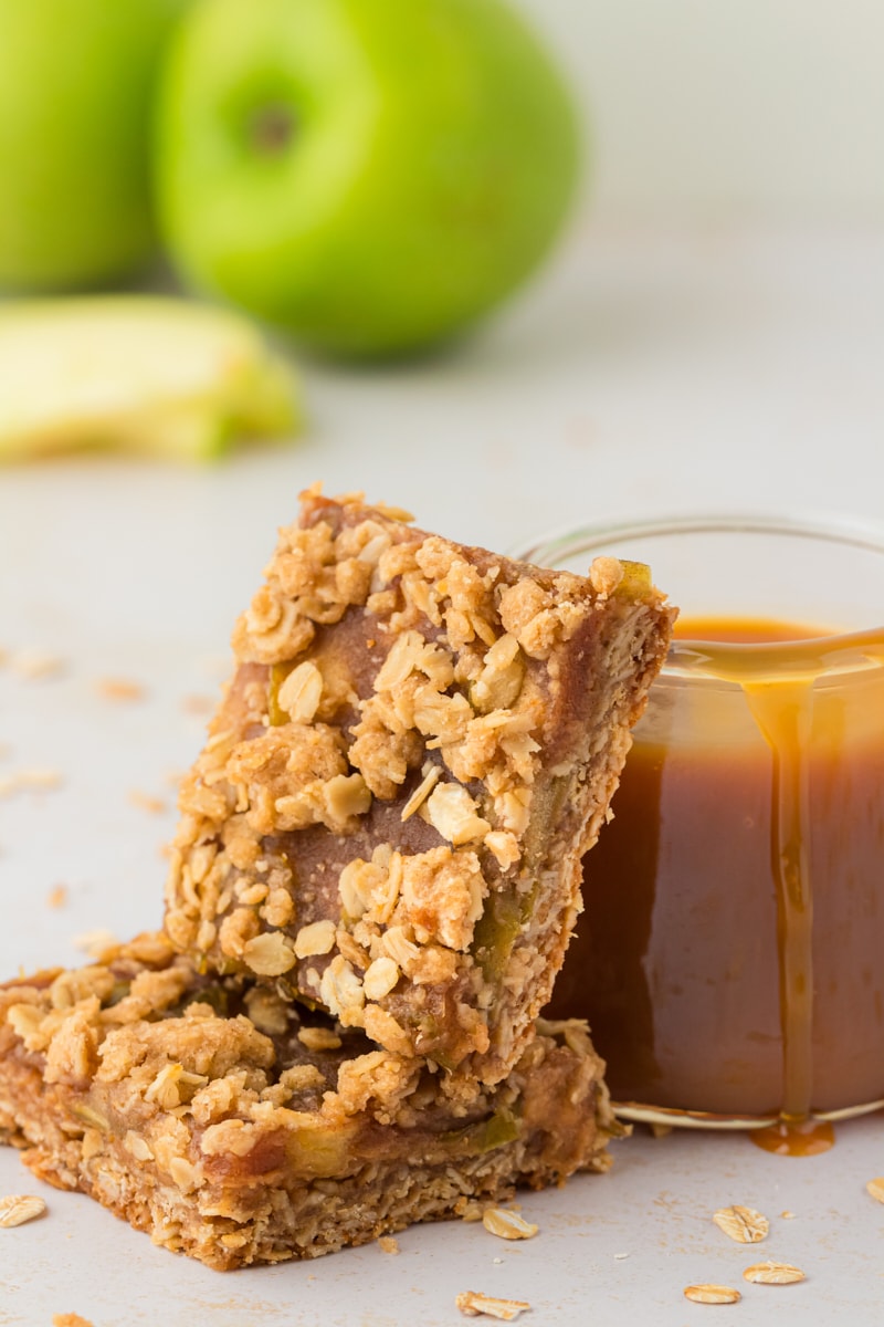 Stack of 2 caramel apple bars leaning against jar of caramel