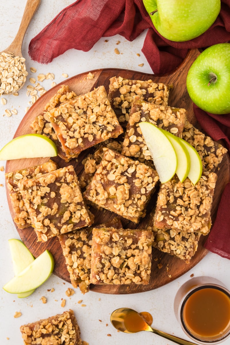 Overhead view of stacked caramel apple bars on round wood cutting board