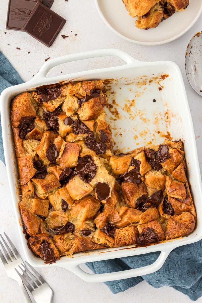 Overhead view of chocolate croissant bread pudding in square baking dish with portion removed