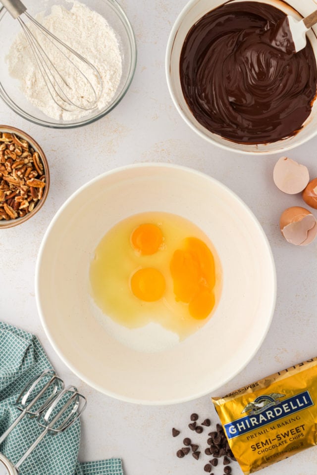 Overhead view of 3 eggs and sugar in mixing bowl